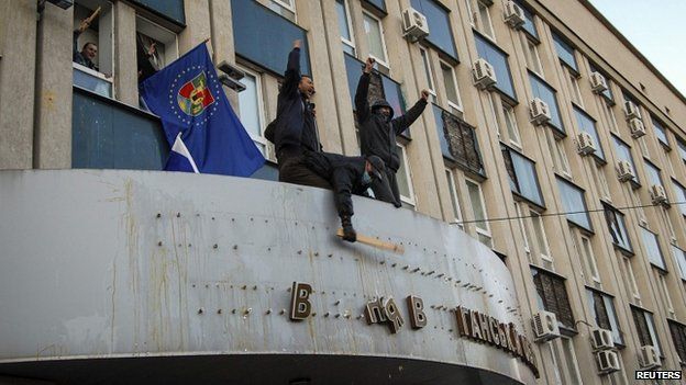 Pro-Russian protesters remove the sign from the state security service building in Luhansk, eastern Ukraine, on 6 April 2014