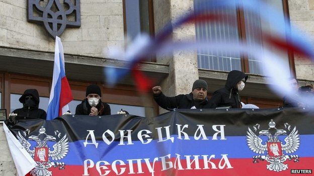 Pro-Russia protesters hang a banner as they storm the regional government building in Donetsk April 6, 2014