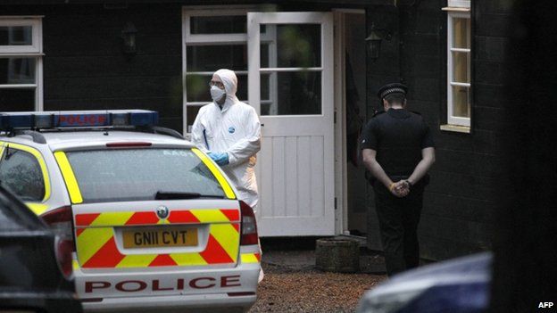 A police officer and forensic officer outside a house
