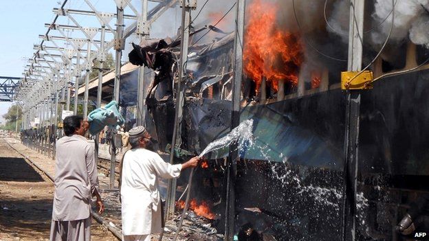 A Pakistani railway official tries to extinguish the fire on the train at Sibi railway station - 8 April 2014