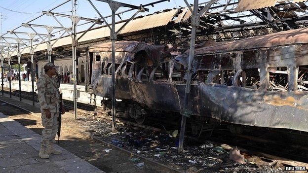 A soldier stands near a damaged passenger carriage at the site of a bomb blast at Sibi train station - 8 April 2014