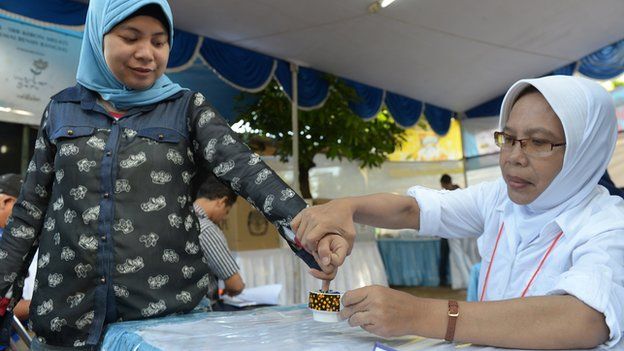 An Indonesian woman (L) has her finger inked after casting her ballot paper during legislative polls in Jakarta on 9 April 2014