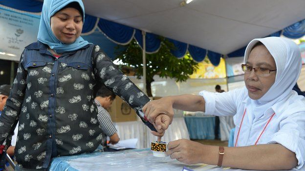 An Indonesian woman (L) has her finger inked after casting her ballot paper during legislative polls in Jakarta on 9 April 2014