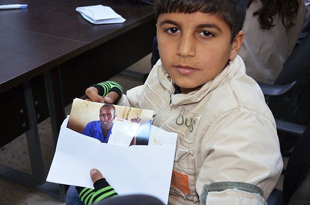 A Syrian boy holds a photo of a Somali refugee who has sent him a letter