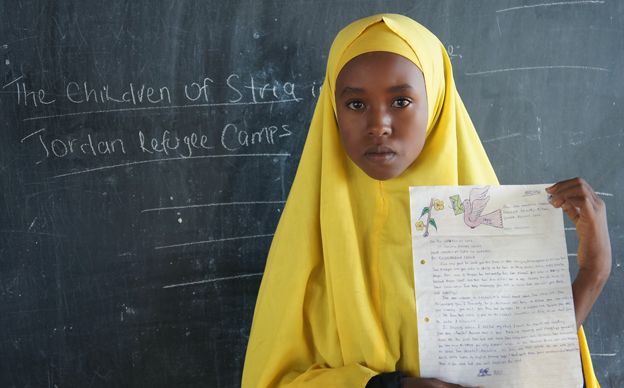 A Somali girl holds up the letter she has written