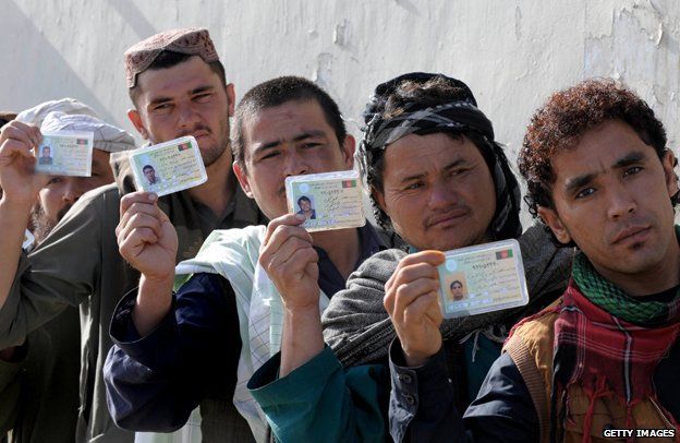 Afghan men holding up ID cards