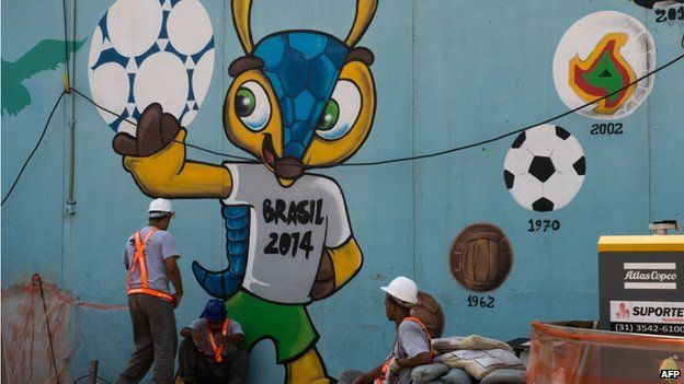 Workers rest next to a graffiti of Fuleco -the mascot of Brazil 2014 FIFA World Cup- near the Maracana metro in Rio de Janeiro on 8 April 2014.