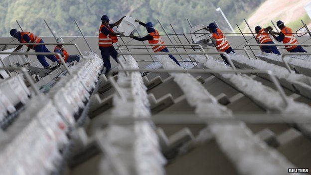 Labourers carry seats as they work on the construction of the Arena de Sao Paulo Stadium, one of the venues for the 2014 World Cup, in the Sao Paulo district of Itaquera on 11 April 2014.