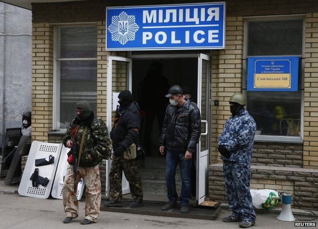 Armed men stand in front of the police headquarters building in Sloviansk, April 12
