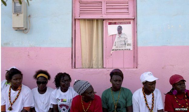 Youth supporters of presidential candidate Jose Maria Vaz sit in front of his poster in Bissau on 11 April