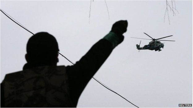 A man gestures while pro-Russian protesters gather at the police headquarters, while a military helicopter flies above, in Sloviansk April 13