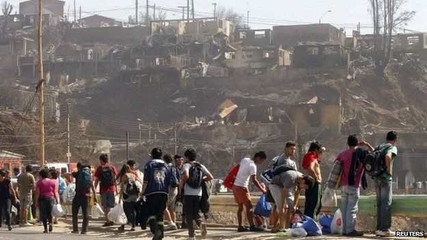 Residents walk carrying their belongings in Valparaiso, April 13, 2014.