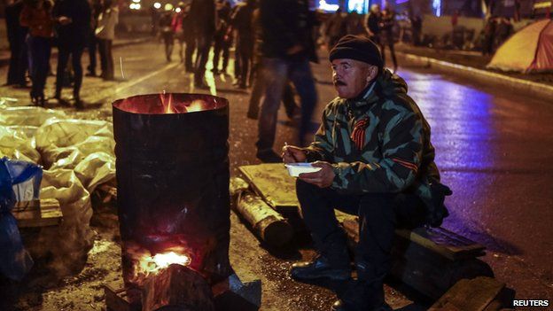 A pro-Russian supporter eats next to a stove on a street near in the seized office of the SBU state security service, in Luhansk, in eastern Ukraine April 13