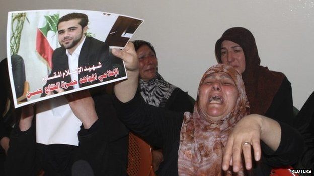 The mother of Hamza Hajj Hassan holds up a photo of the al-Manar reporter at her home in Shaath (15 April 2014)