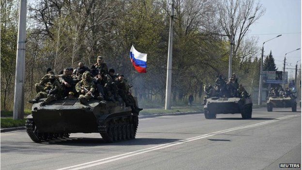 Armed men, wearing black and orange ribbons of St. George - a symbol widely associated with pro-Russia protests - drive an airborne combat vehicle with a Russian flag on top, outside Kramatorsk