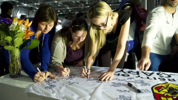 University of Calgary students and staff sign condolences on a University of Calgary banner during a memorial service for victims of the multiple fatal stabbing in northwest Calgary, Alberta 15 April 2014
