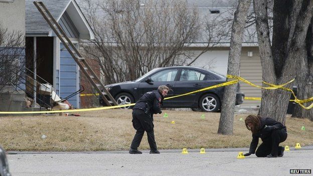 Police officers mark and photograph evidence at a house where five people were stabbed in the early morning hours in Calgary, Alberta, 15 April 2014