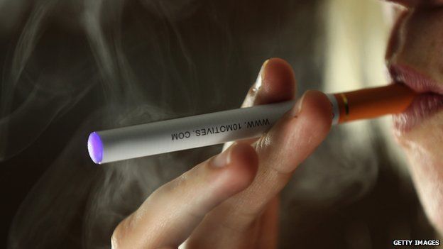 A a close-up photograph of a woman smoking an e-cigarette.
