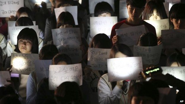 Students hold papers with candles as they pray for the safe return of their friends aboard the sunken ferry Sewol at Danwon High School in Ansan, south of Seoul, South Korea, Friday, April 18, 2014