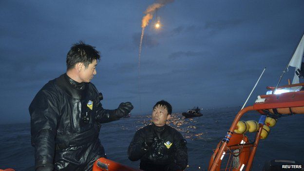 Search and rescue workers operate near the area where passenger ship "Sewol" capsized off Jindo as lighting flares are released in the sky during a night search on April 18