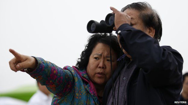Song and his wife, whose granddaughter was on South Korean ferry Sewol which sank in the sea off Jindo and has been missing, look at the sea with a pair of binoculars in Jindo 19 April