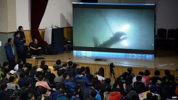 Relatives watch underwater footage of divers reaching the the sunken South Korean ferry - 19 April 2014