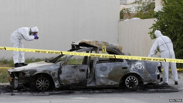 A police forensic team collect evidence at the scene of a car explosion in a village near Manama, Bahrain - 19 April 2014