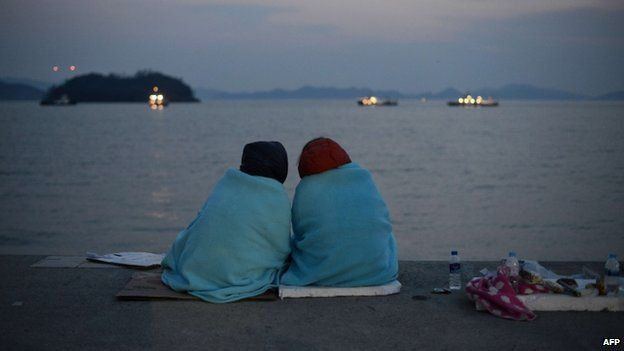 Relatives of victims of the South Korean ferry Sewol sit before the sea at Jindo harbour on 20 April 2014