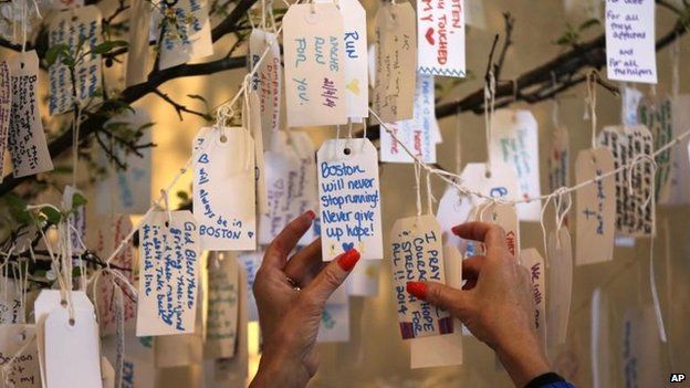 A visitor hangs a message on a tree at the Dear Boston exhibit at the Boston Public Library, 20 April