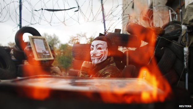A pro-Russia protester wearing a Guy Fawkes mask sits on a barricade outside a regional government building in Donetsk, in eastern Ukraine April 20