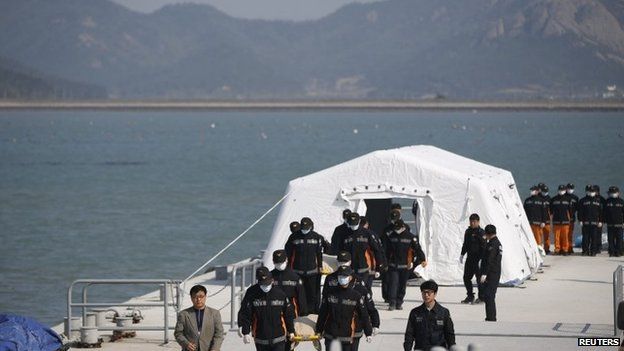 Rescue workers carry the bodies of passengers who were on the capsized Sewol passenger ship, which sank in the sea off Jindo, at a port where family members of missing passengers have gathered, in Jindo on 21 April 2014