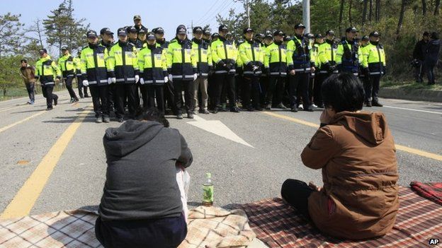 Relatives of missing passengers aboard the sunken ferry Sewol weep in front of policemen as they try to march toward the presidential house to protest the government's rescue operation in Jindo, South Korea, on 20 April 2014