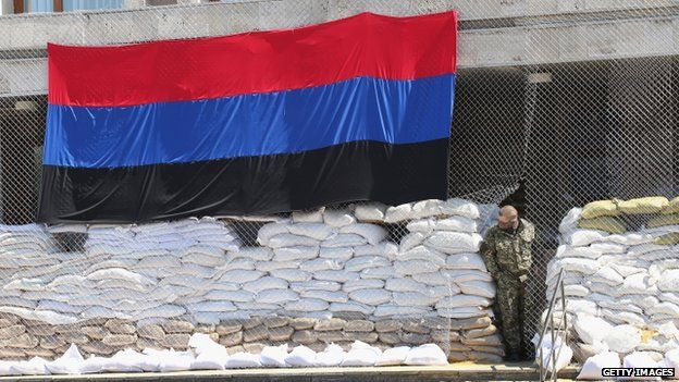A pro-Russian militant looks out from the barricaded entrance of the city council building on 21 April 2014 in Sloviansk