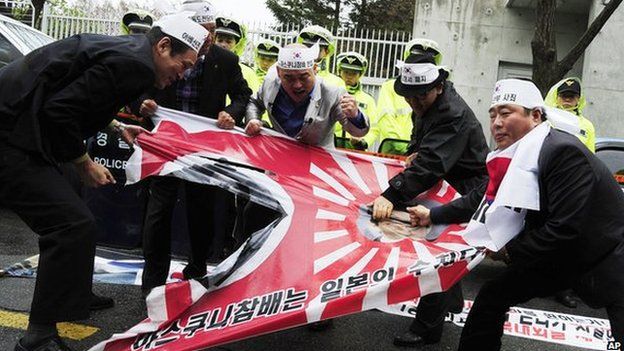South Korean protesters tear a Japanese wartime flag during a rally to protest against Japanese lawmakers" visit to Yasukuni Shrine
