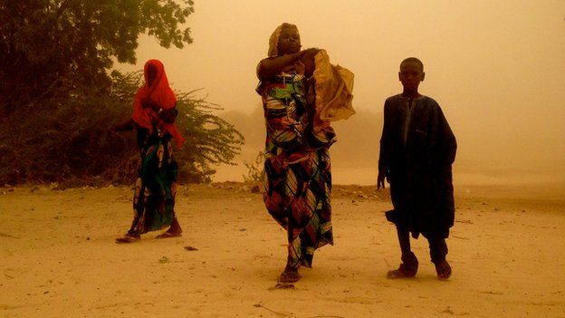 Women and child from the Nigerian village of Gashagar wade through sandstorm on Niger side of the border, where they sought refuge