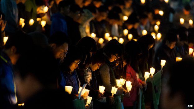 People hold candles at a vigil for students among the missing passengers of a South Korean capsized ferry, in central Ansan on 22 April 2014.