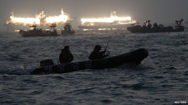 South Korean rescue workers conduct their rescue operation at the area where the capsized passenger ship Sewol sank, as fishing boats emit light, in Jindo on 22 April 2014.