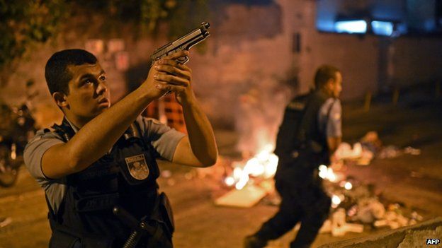 A Brazilian Police Special Forces member takes position during a violent protest in a favela near Copacabana in Rio de Janeiro, Brazil on 22 April 2014