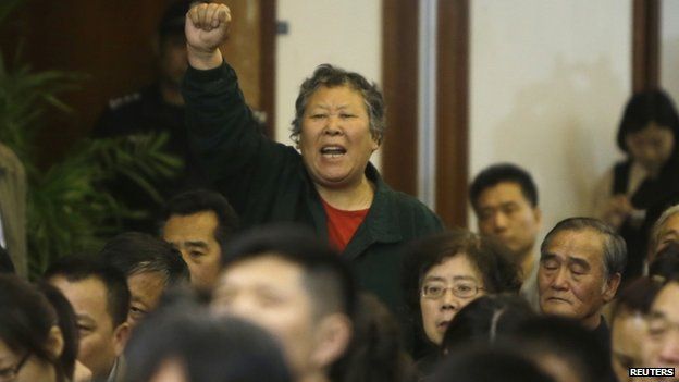 A relative of a passenger aboard MH370 gestures as she shouts at Malaysian representatives during a briefing at Lido Hotel in Beijing (21 April 2014)