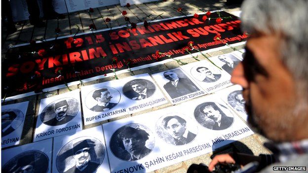 A person looks at portraits and a sign reading "1915 is a Genocide. Genocide is a crimes against humanity" during a demonstration on 24 April 2013 in Istanbul