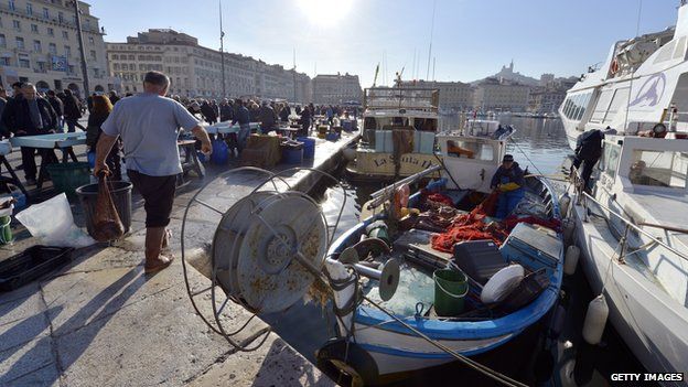 A fisherman works on his boat next to a fish market in the Vieux Port of Marseille in January 2013