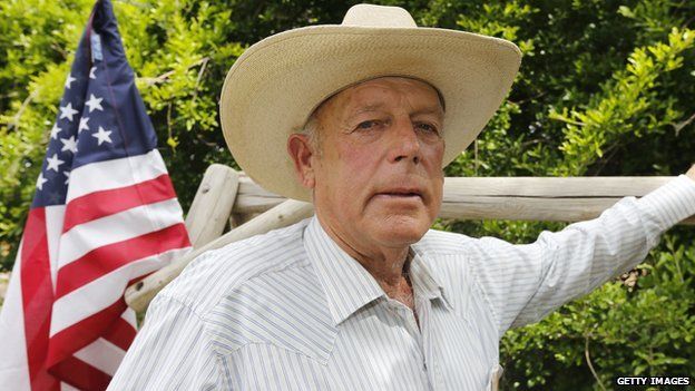 Nevada rancher Cliven Bundy stands in front of an American flag.