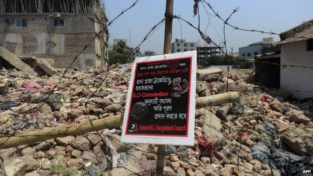A poster tied to a fence at the scene of the Bangladesh Rana Plaza building collapse and reading, "We want a safe work place, not a death trap" is seen on the first anniversary of the disaster on the outskirts of Dhaka on April 24, 2014