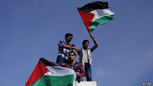 Palestinians hold national flags as they celebrate the reconciliation agreement in Gaza City - 23 April 2014