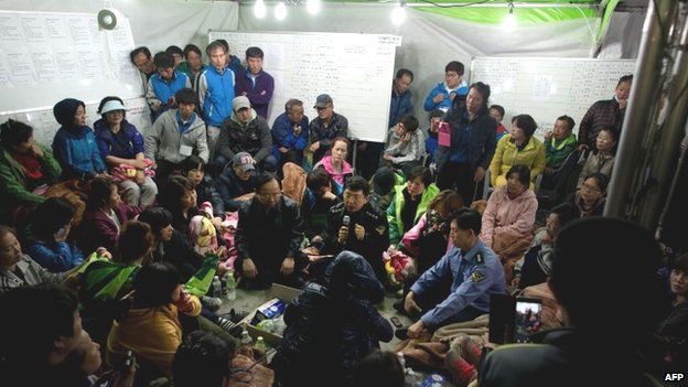 Coastguard police chief Kim Seouk Gyun (bottom centre), vice coastguard police chief Choi Sang Han (bottom right), and South Korean minister of Oceans and Fisheries Lee Ju Young (bottom left) attend a meeting with relatives of victims of the ferry disaster at Jindo harbour