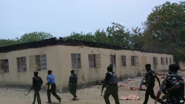 In this photo taken Monday, April, 21. 2014. Security walk past burned government secondary school Chibok, were gunmen abducted more than 200 students in Chibok, Nigeria.