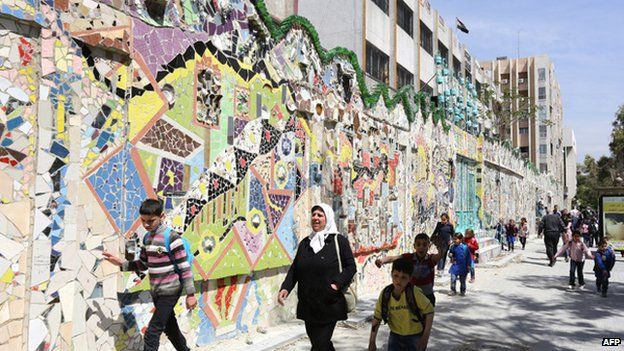 Syrian schoolchildren walk past a record-breaking mural in the al-Mazzeh neighbourhood