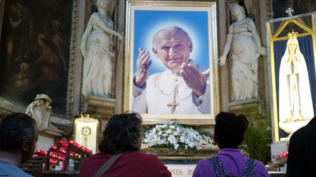 Worshippers/portrait of John Paul II in church
