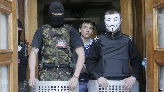 Masked pro-Russian activists guard the entrance during their mass storming of a regional TV centre in Donetsk