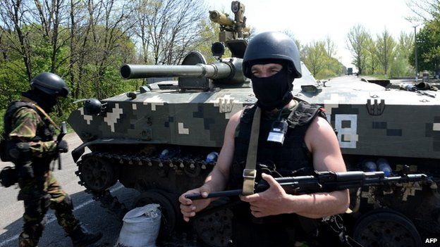 A Ukrainian soldier stands by an amoured personnel carriers at a check-point about 25 km from Sloviansk